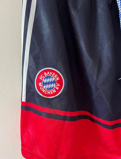 Maillot de foot vintage extérieur noir du Bayern Munich 1997/1998. On peut retrouver l'équipementier Adidas et le sponsor Opel. Le maillot est accompagné de son short d'époque. Il s'agit d'un maillot et d'un short authentique.