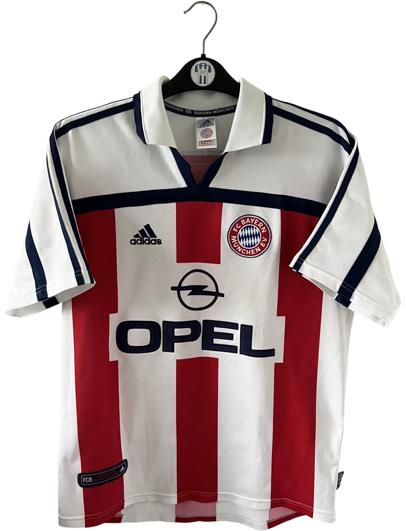 Maillot de foot vintage extérieur blanc du Bayern Munich de la saison 2000/2002. On peut retrouver l'équipementier Adidas et le sponsor Opel. Il s'agit d'un maillot authentique d'époque.