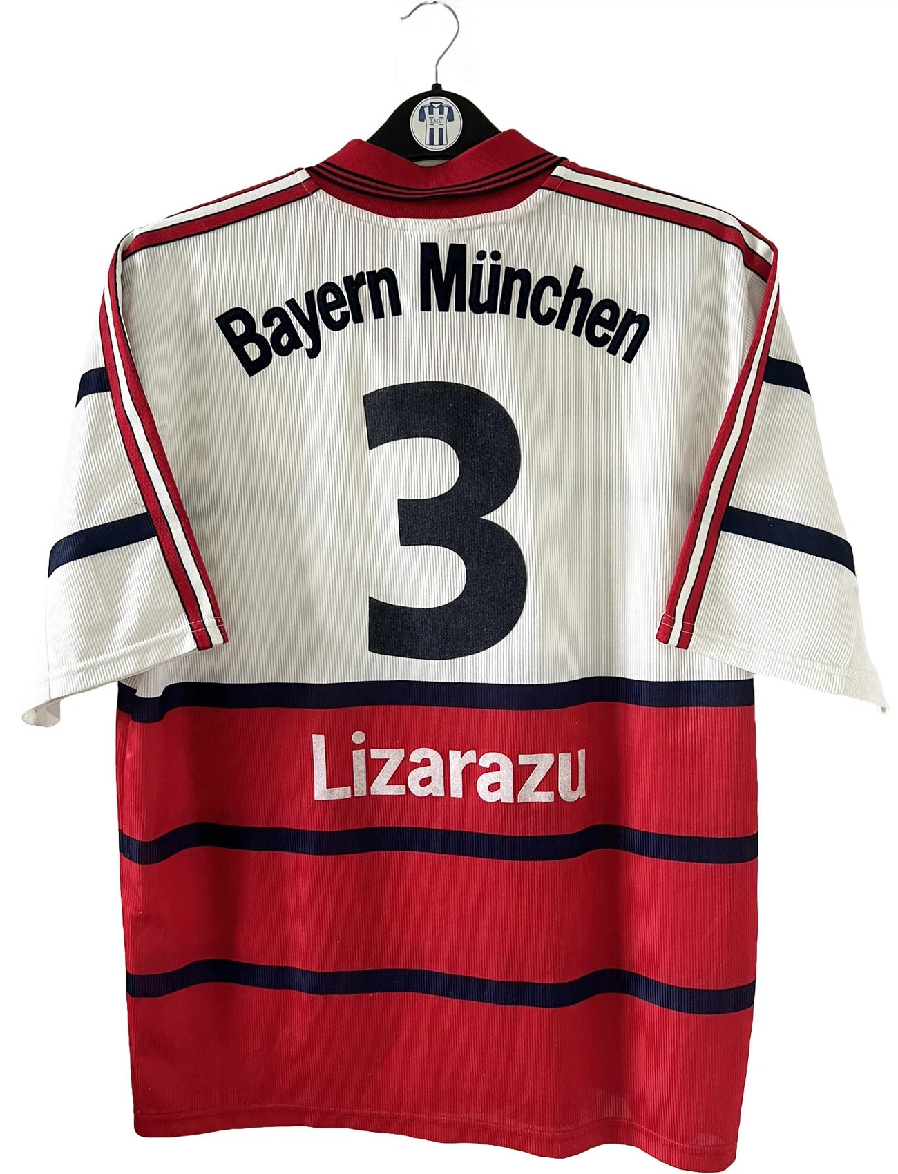 Maillot de foot vintage extérieur blanc et rouge du bayern munich de la saison 1998/1999. On peut retrouver l'équipementier Adidas et le sponsor Opel. Le maillot est floqué du numéro 3 Bixente Lizarazu. Il s'agit d'un maillot authentique d'époque.
