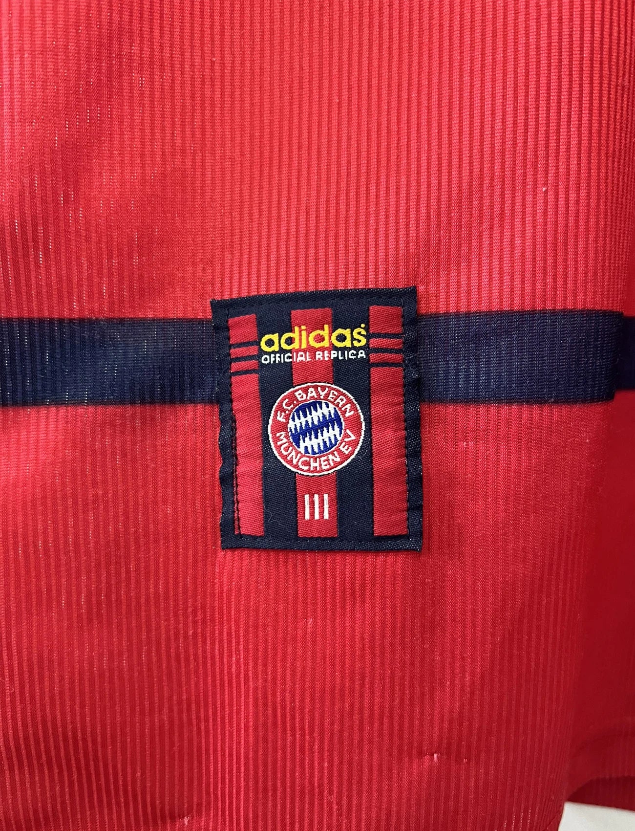 Maillot de foot vintage extérieur blanc et rouge du bayern munich de la saison 1998/1999. On peut retrouver l'équipementier Adidas et le sponsor Opel. Le maillot est floqué du numéro 3 Bixente Lizarazu. Il s'agit d'un maillot authentique d'époque.