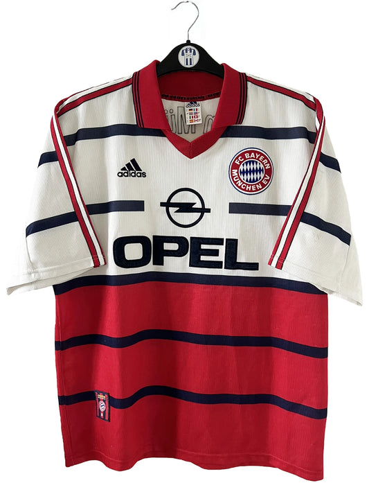 Maillot de foot vintage extérieur blanc et rouge du bayern munich de la saison 1998/1999. On peut retrouver l'équipementier Adidas et le sponsor Opel. Le maillot est floqué du numéro 3 Bixente Lizarazu. Il s'agit d'un maillot authentique d'époque.