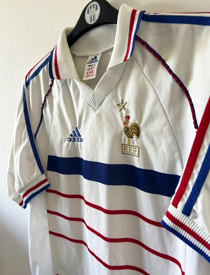 Maillot de foot vintage extérieur blanc de l'équipe de france 1998. On peut retrouver l'équipementier Adidas. Il s'agit d'un maillot authentique d'époque.