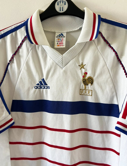 Maillot de foot vintage extérieur blanc de l'équipe de france 1998. On peut retrouver l'équipementier Adidas. Il s'agit d'un maillot authentique d'époque.