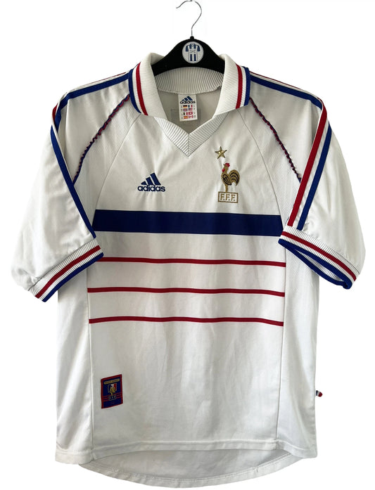 Maillot de foot vintage extérieur blanc de l'Equipe de France 1998. On peut retrouver l'équipementier Adidas. Il s'agit d'un maillot authentique d'époque.