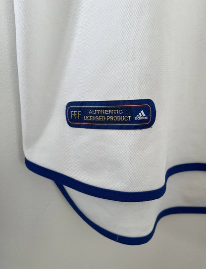 Maillot de foot vintage extérieur blanc de l'équipe de france 2000. On peut retrouver l'équipementier adidas. Il s'agit d'un maillot authentique d'époque comportant l'étiquette 647189.