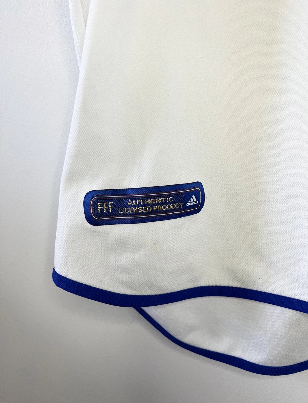 Maillot de foot vintage extérieur blanc de l'équipe de france 2000. On peut retrouver l'équipementier adidas. Il s'agit d'un maillot authentique d'époque comportant l'étiquette 647189.