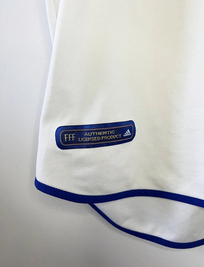 Maillot de foot vintage extérieur blanc de l'équipe de france 2000. On peut retrouver l'équipementier adidas. Il s'agit d'un maillot authentique d'époque comportant l'étiquette 647189.