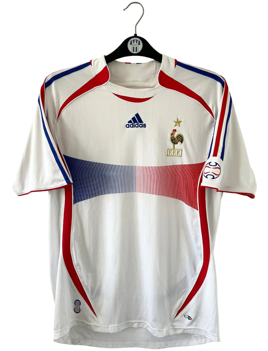 Maillot de foot vintage extérieur blanc de l'équipe de France 2006. On peut retrouver l'équipementier Adidas. Il s'agit d'un maillot authentique d'époque comportant l'étiquette 740125