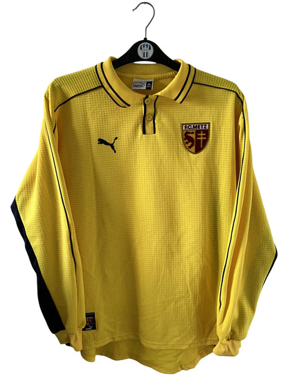 Maillot de foot vintage extérieur jaune du FC Metz de la saison 1999/2000. On peut retrouver l'équipementier Puma. Il s'agit d'un maillot authentique d'époque, issu du stock pro du FC Metz.