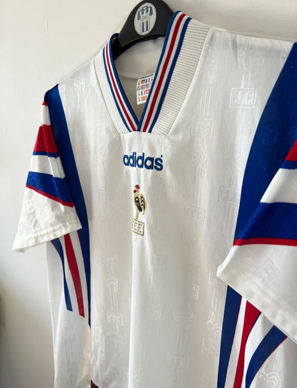 Maillot de foot vintage extérieur blanc de l'équipe de france 1996. On peut retrouver l'équipementier Adidas. Il s'agit d'un maillot authentique d'époque.