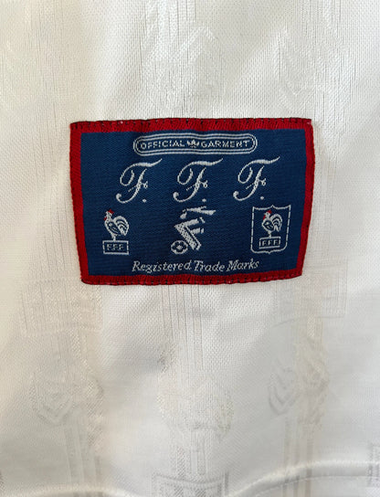 Maillot de foot vintage extérieur blanc de l'équipe de france 1996. On peut retrouver l'équipementier Adidas. Il s'agit d'un maillot authentique d'époque.