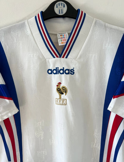 Maillot de foot vintage extérieur blanc de l'équipe de france 1996. On peut retrouver l'équipementier Adidas. Il s'agit d'un maillot authentique d'époque.