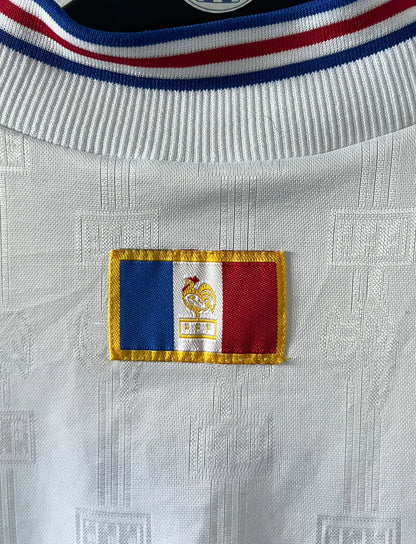 Maillot foot vintage domicile blanc de l'équipe de france 1996. On peut retrouver l'équipementier Adidas. Il s'agit d'un maillot authentique d'époque.
