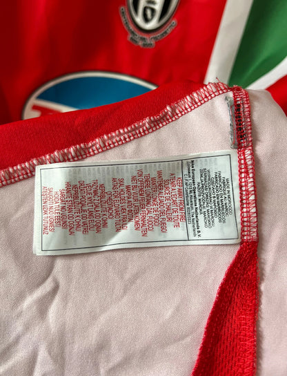 Maillot de foot vintage extérieur orange de la Juventus 2005/2006. On peut retrouver l'équipementier Nike et le sponsor Tamoil. Il s'agit du maillot du centenaire pour le premier scudetto. Il s'agit d'un maillot authentique d'époque.