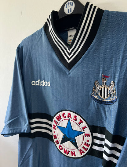 Maillot de foot vintage extérieur bleu de Newcastle de la saison 1996/1997. On peut retrouver l'équipementier Adidas et le sponsor Newcastle Brown Ale. Il s'agit d'un maillot authentique d'époque.