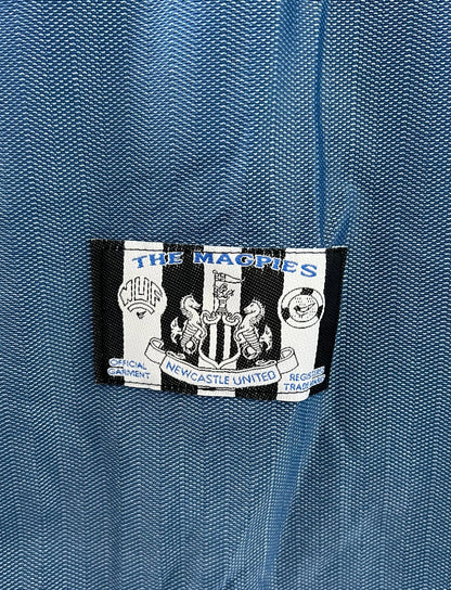 Maillot de foot vintage extérieur bleu de Newcastle de la saison 1996/1997. On peut retrouver l'équipementier Adidas et le sponsor Newcastle Brown Ale. Il s'agit d'un maillot authentique d'époque.