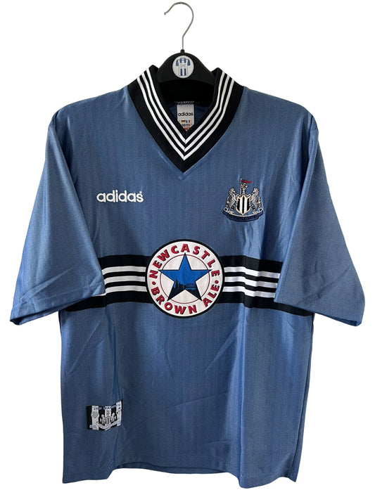 Maillot de foot vintage extérieur bleu de Newcastle de la saison 1996/1997. On peut retrouver l'équipementier Adidas et le sponsor Newcastle Brown Ale. Il s'agit d'un maillot authentique d'époque.