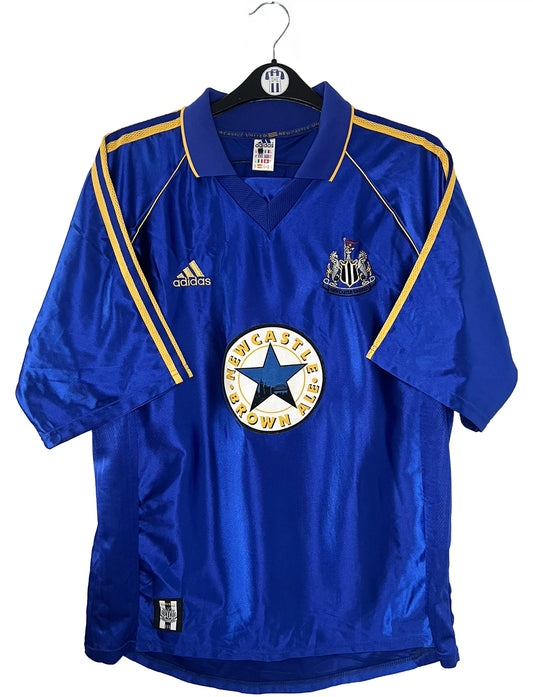 Maillot de foot vintage extérieur bleu de Newcastle de la saison 1998/1999. On peut retrouver l'équipementier Adidas et le sponsor Newcastle Brown Ale. Il s'agit d'un maillot authentique d'époque.