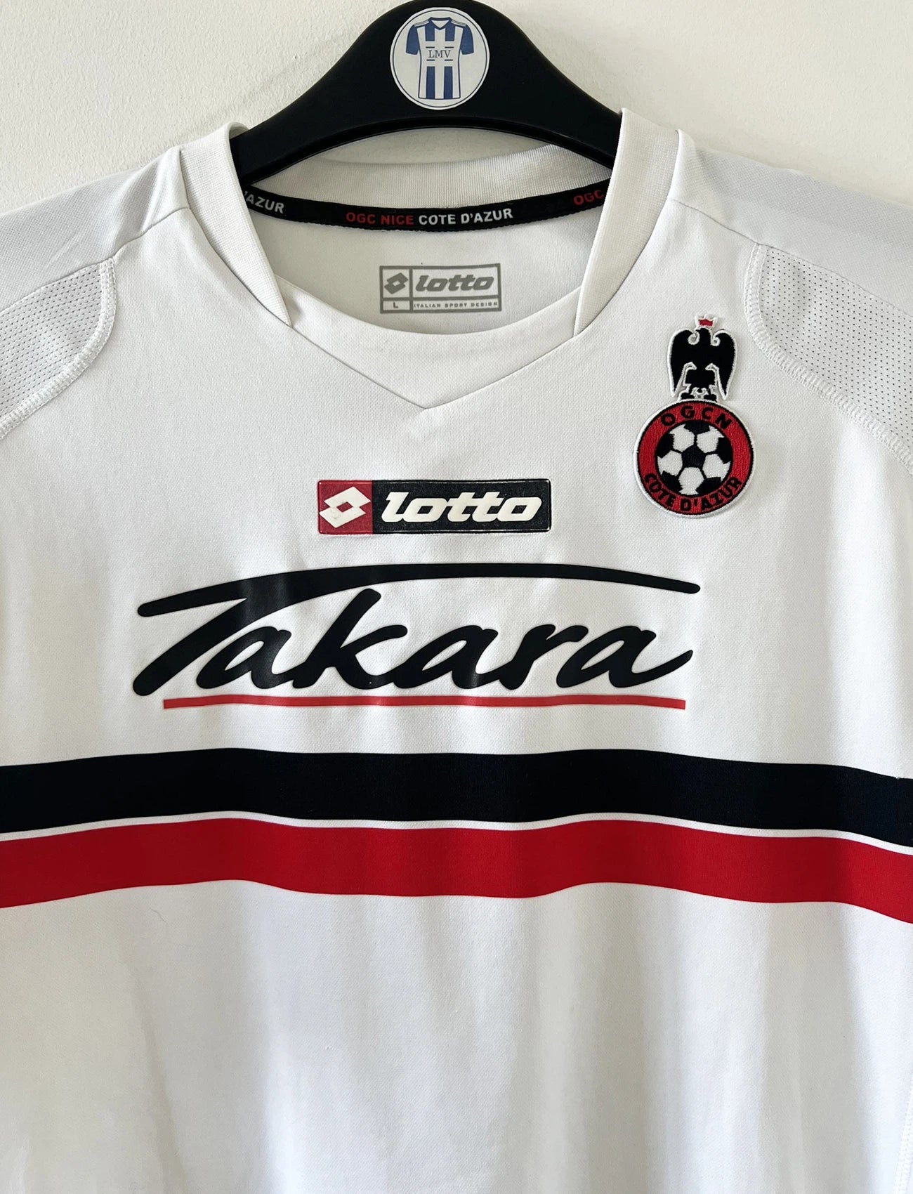 Maillot de foot vintage extérieur blanc de l'ogc nice de la saison 2008/2009. On peut retrouver l'équipementier Lotto et le sponsor Takara. Le maillot est floqué du numéro 6 Echouafni. ll s'agit d'un maillot authentique d'époque.
