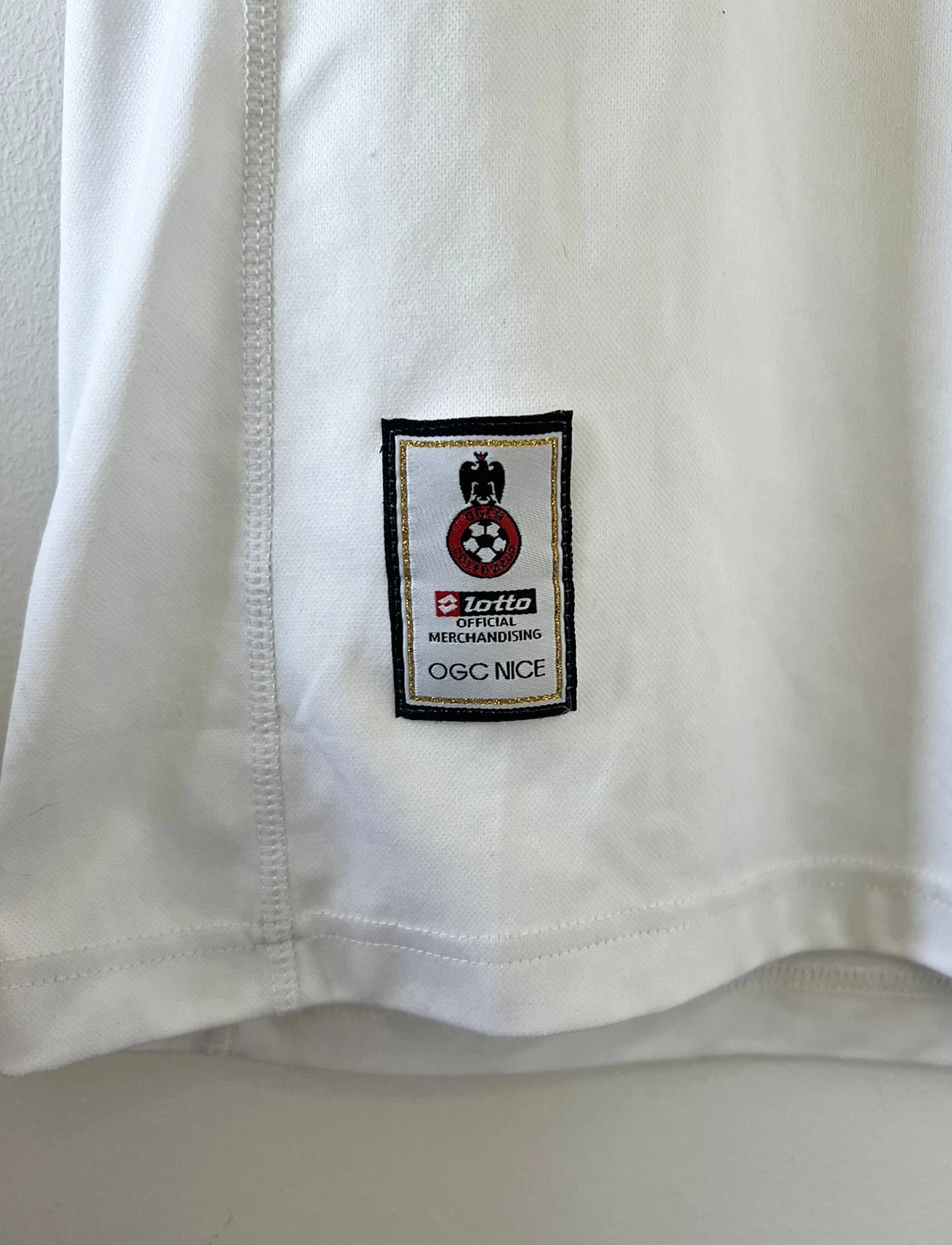Maillot de foot vintage extérieur blanc de l'ogc nice de la saison 2008/2009. On peut retrouver l'équipementier Lotto et le sponsor Takara. Le maillot est floqué du numéro 6 Echouafni. ll s'agit d'un maillot authentique d'époque.