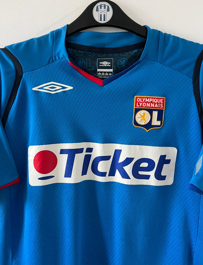 Maillot foot vintage extérieur bleu de l'OL saison 2008/2009. On peut retrouver l'équipementier Umbro et le sponsor Ticket. Il s'agit d'un maillot authentique d'époque.