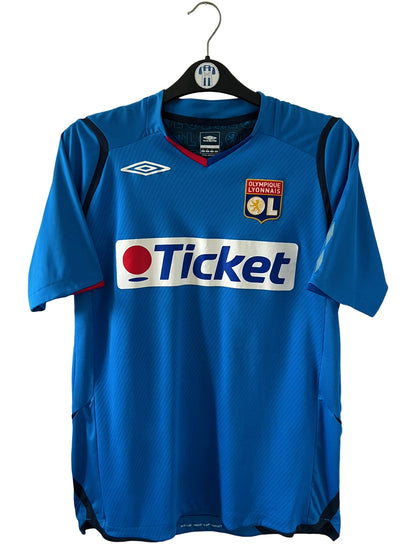 Maillot foot vintage extérieur bleu de l'OL saison 2008/2009. On peut retrouver l'équipementier Umbro et le sponsor Ticket. Il s'agit d'un maillot authentique d'époque.
