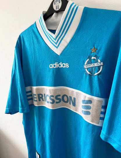Maillot de foot vintage bleu extérieur de l'OM 1997/1998. On peut retrouver l'équipementier Adidas et le sponsor Ericsson. Il s'agit d'un maillot authentique d'époque.