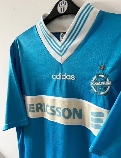 Maillot de foot vintage extérieur bleu de l'OM de la saison 1997/1998. On peut retrouver l'équipementier Adidas et le sponsor Ericsson. Il s'agit d'un maillot authentique d'époque.