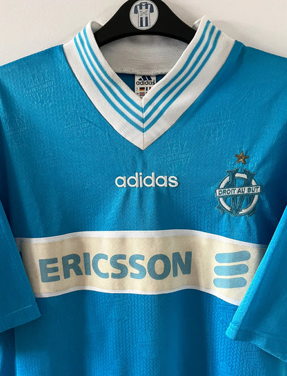Maillot de foot vintage extérieur bleu de l'OM de la saison 1997/1998. On peut retrouver l'équipementier Adidas et le sponsor Ericsson. Il s'agit d'un maillot authentique d'époque.
