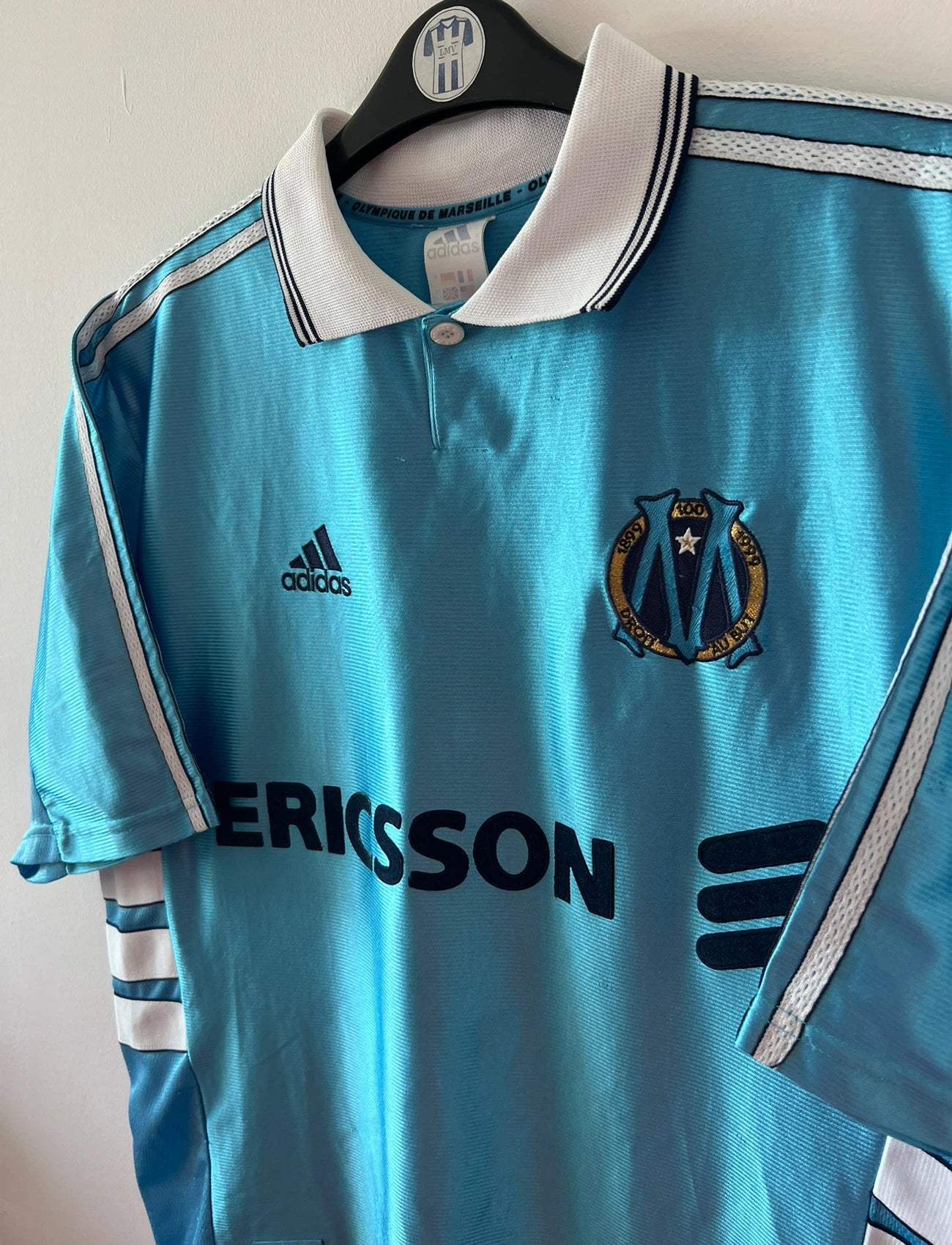 Maillot de foot vintage extérieur bleu de l'OM 1998. On peut retrouver l'équipementier Adidas et le sponsor Ericsson. Il s'agit d'un maillot authentique d'époque.