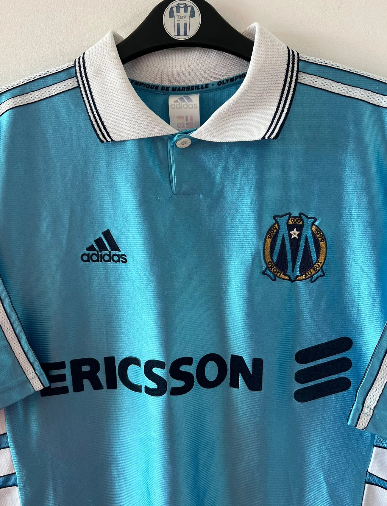 Maillot de foot vintage extérieur bleu de l'OM 1998. On peut retrouver l'équipementier Adidas et le sponsor Ericsson. Il s'agit d'un maillot authentique d'époque.