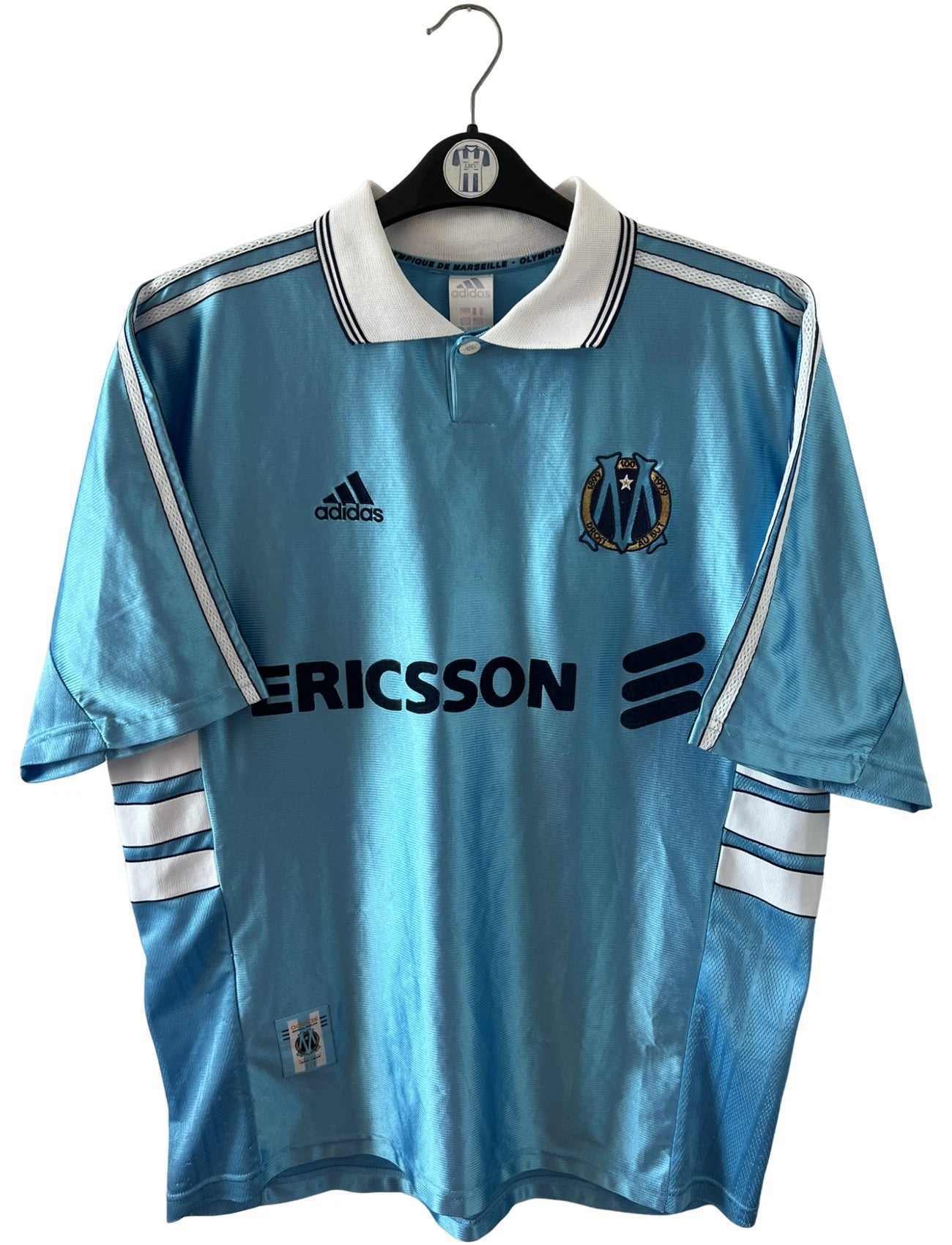 Maillot de foot vintage extérieur bleu de l'OM 1998. On peut retrouver l'équipementier Adidas et le sponsor Ericsson. Il s'agit d'un maillot authentique d'époque.