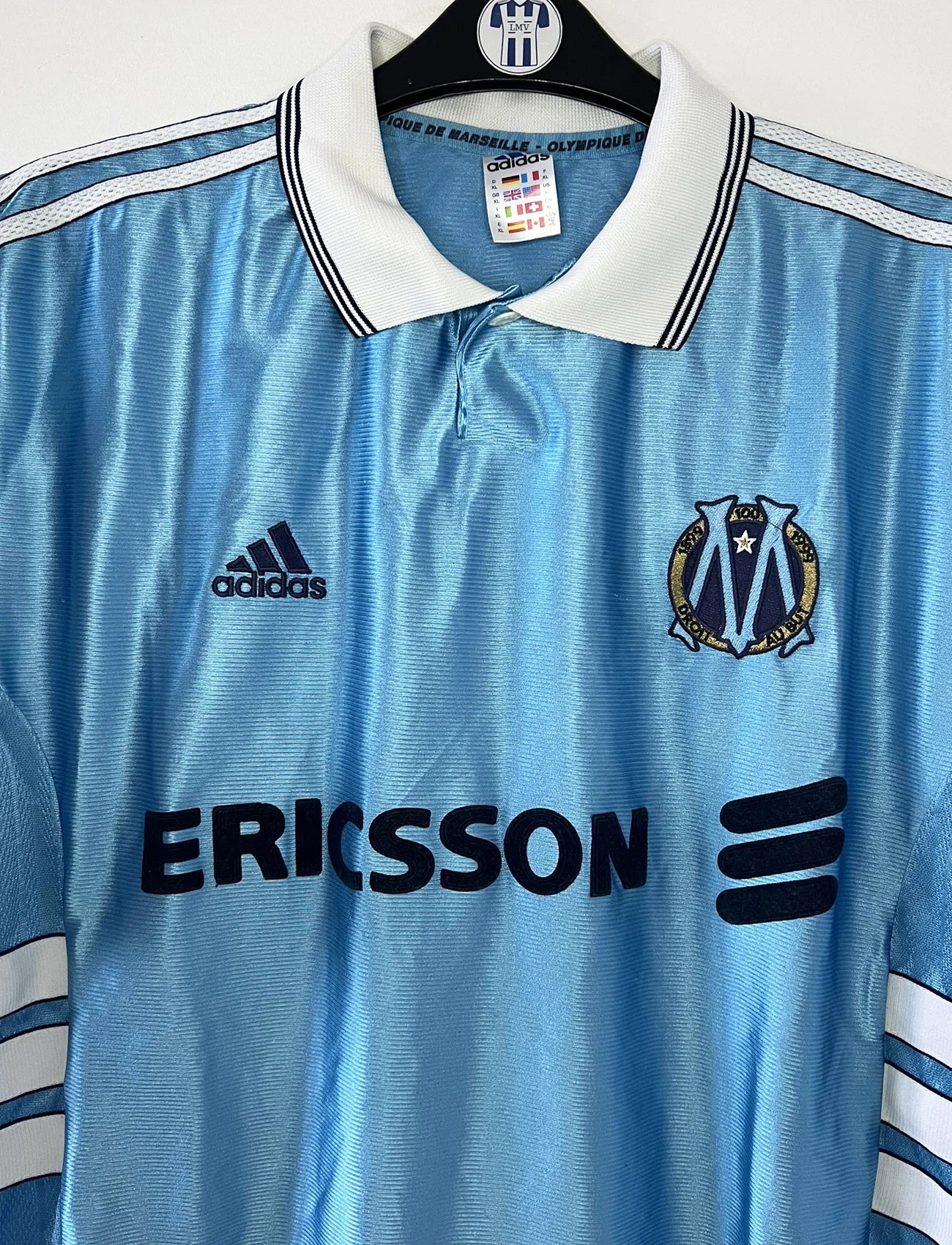 Maillot de foot vintage extérieur bleu de l'Olympique de Marseille de la saison 1998/1999. On peut retrouver l'équipementier Adidas et le sponsor Ericsson. Il s'agit d'un maillot authentique d'époque.