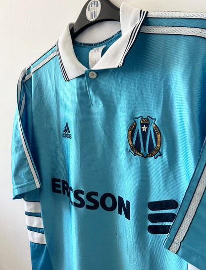 Maillot de foot vintage extérieur bleu de l'OM 1998/1999. On peut retrouver l'équipementier Adidas et le sponsor Ericsson. Il s'agit d'un maillot authentique d'époque.