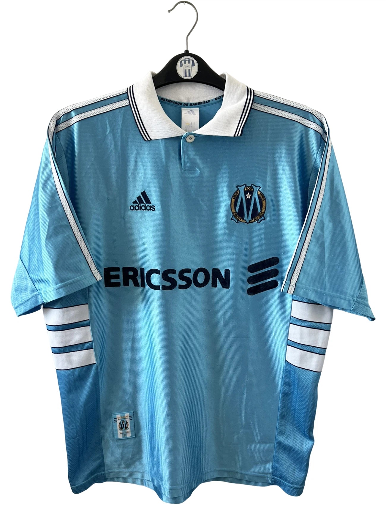 Maillot de foot vintage extérieur bleu de l'OM 1998/1999. On peut retrouver l'équipementier Adidas et le sponsor Ericsson. Il s'agit d'un maillot authentique d'époque.