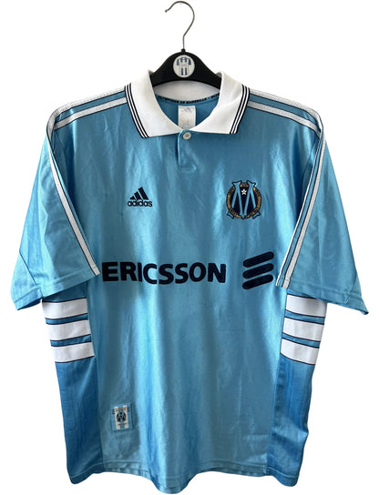 Maillot de foot vintage extérieur bleu de l'OM 1998/1999. On peut retrouver l'équipementier Adidas et le sponsor Ericsson. Il s'agit d'un maillot authentique d'époque.