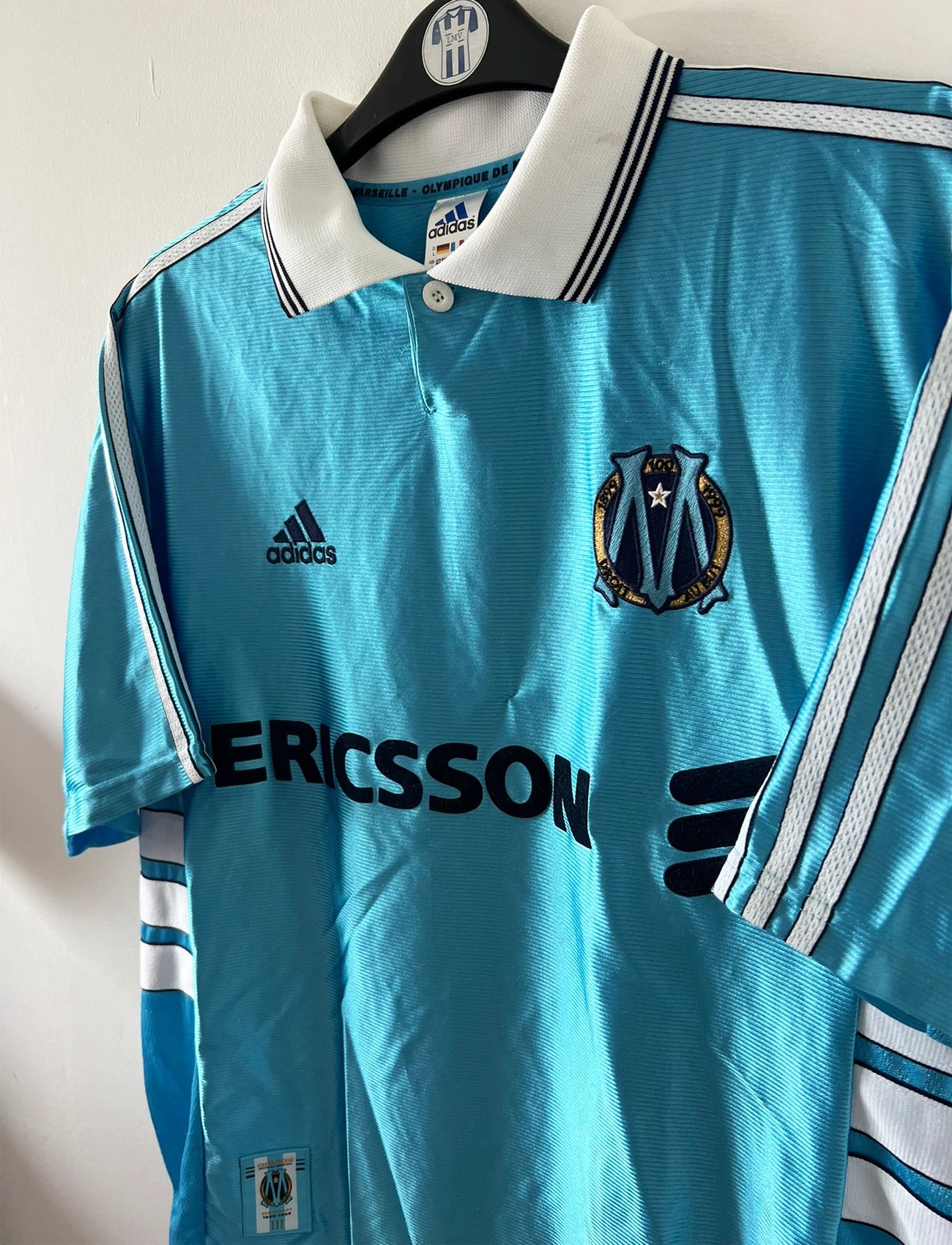 Maillot de foot vintage extérieur bleu de l'OM 1998. On peut retrouver l'équipementier Adidas et le sponsor Ericsson. Il s'agit d'un maillot authentique d'époque.
