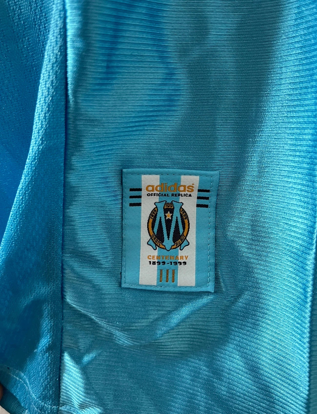 Maillot de foot vintage extérieur bleu de l'OM 1998. On peut retrouver l'équipementier Adidas et le sponsor Ericsson. Il s'agit d'un maillot authentique d'époque.