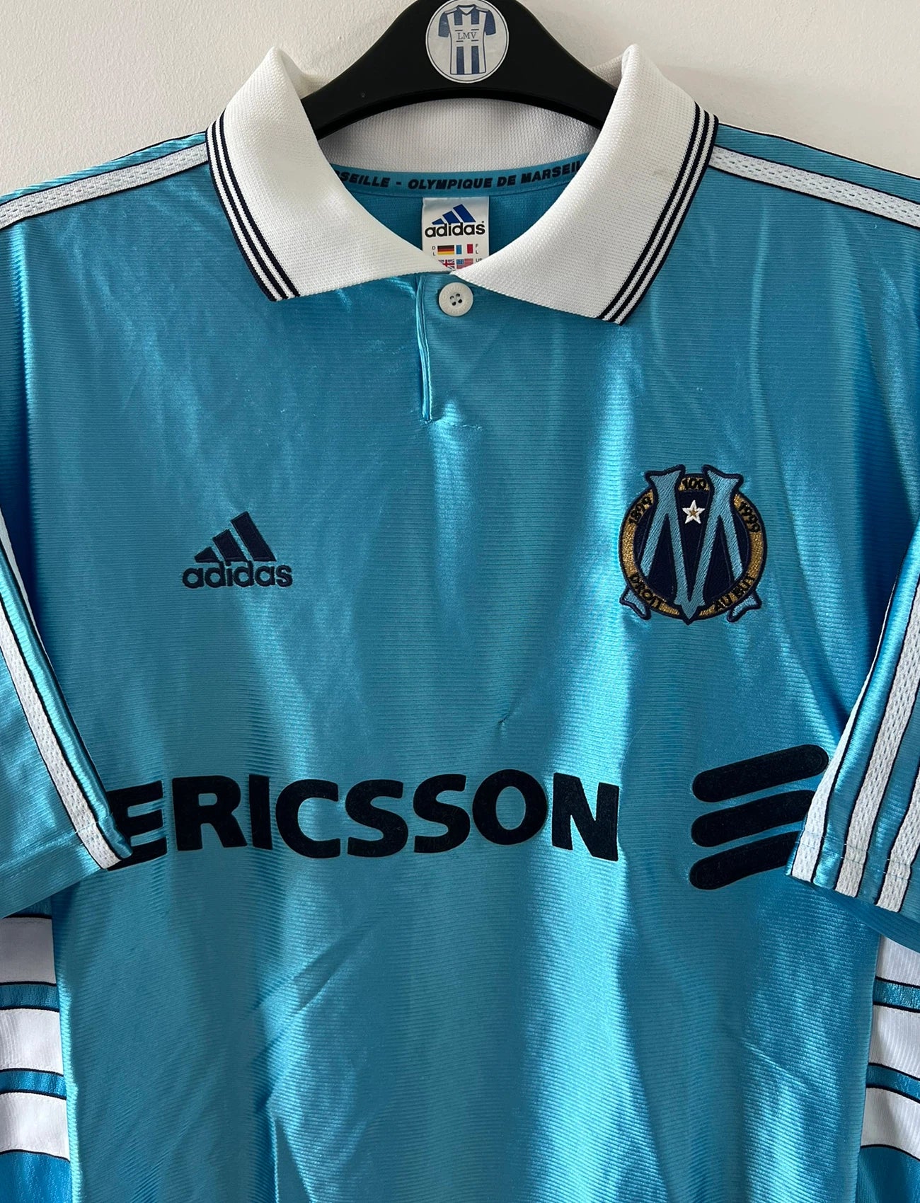 Maillot de foot vintage extérieur bleu de l'OM 1998. On peut retrouver l'équipementier Adidas et le sponsor Ericsson. Il s'agit d'un maillot authentique d'époque.