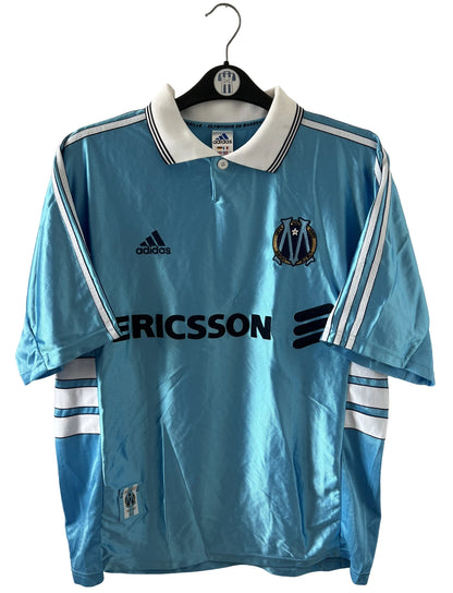 Maillot de foot vintage extérieur bleu de l'OM 1998. On peut retrouver l'équipementier Adidas et le sponsor Ericsson. Il s'agit d'un maillot authentique d'époque.