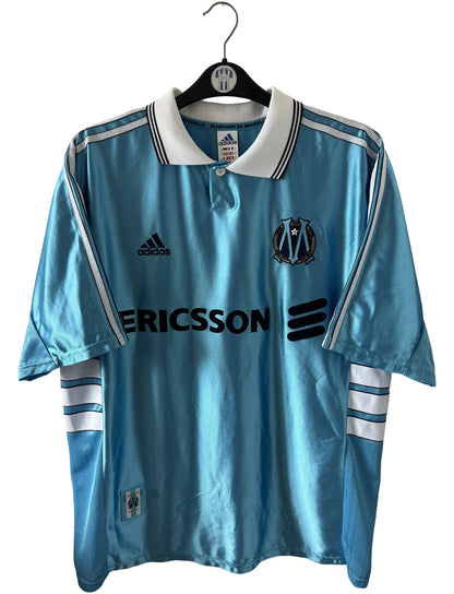 Maillot de foot vintage bleu de l'OM 1998/1999 du centenaire. On peut retrouver l'équipementier Adidas et le sponsor Ericsson. Il s'agit d'un maillot authentique d'époque.