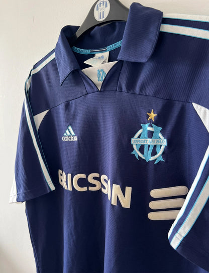 Maillot de foot vintage bleu de l'OM 1999/2000. On peut retrouver l'équipementier Adidas et le sponsor Ericsson. Il s'agit d'un maillot authentique d'époque.