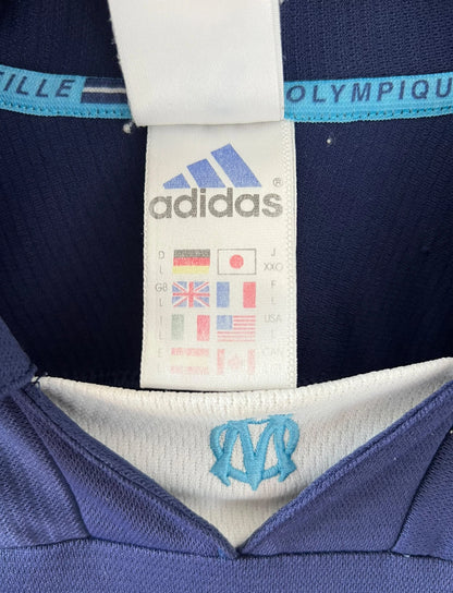 Maillot de foot vintage bleu de l'OM 1999/2000. On peut retrouver l'équipementier Adidas et le sponsor Ericsson. Il s'agit d'un maillot authentique d'époque.