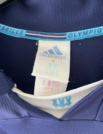 Maillot de foot vintage bleu de l'OM 1999/2000. On peut retrouver l'équipementier Adidas et le sponsor Ericsson. Il s'agit d'un maillot authentique d'époque.