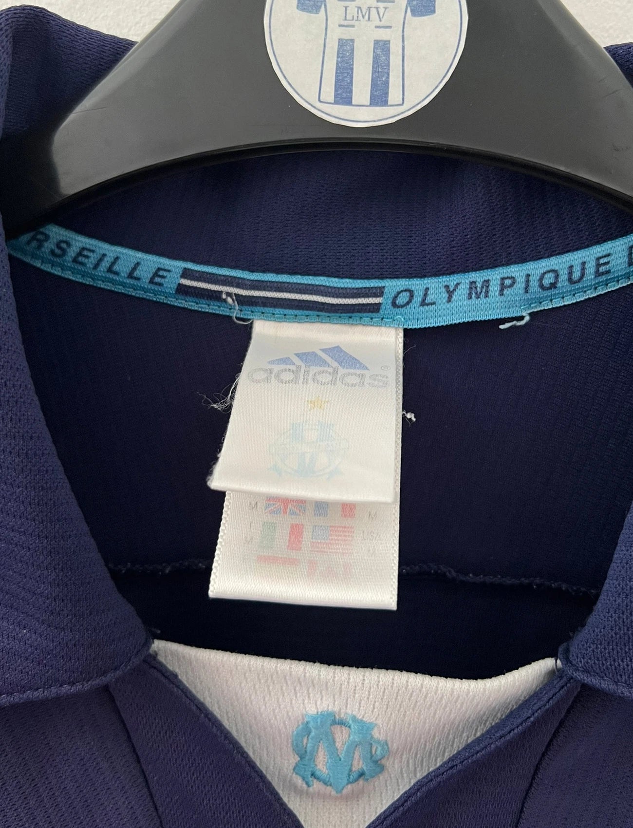 Maillot de foot vintage OM 1999/2000 extérieur bleu. On peut retrouver l'équipementier Adidas et le sponsor Ericsson. Il s'agit d'un maillot authentique d'époque.