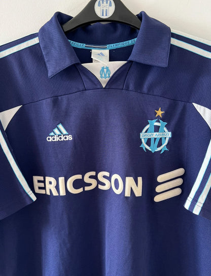 Maillot de foot vintage bleu de l'OM 1999/2000. On peut retrouver l'équipementier Adidas et le sponsor Ericsson. Il s'agit d'un maillot authentique d'époque.