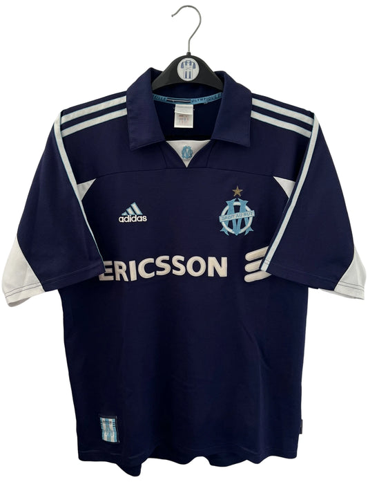 Maillot de foot vintage OM 1999/2000 extérieur bleu. On peut retrouver l'équipementier Adidas et le sponsor Ericsson. Il s'agit d'un maillot authentique d'époque.