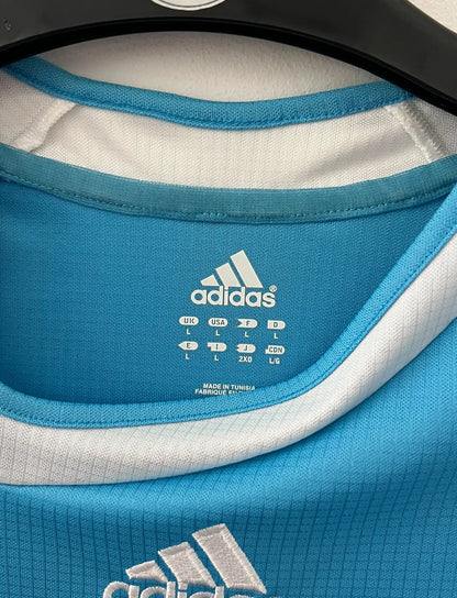 Maillot de foot vintage extérieur bleu et blanc de l'OM 2006/2007. On peut retrouver l'équipementier Adidas et le sponsor Neuf. Le maillot est floqué du numéro 7 Franck Ribery. Il s'agit d'un maillot authentique d'époque.