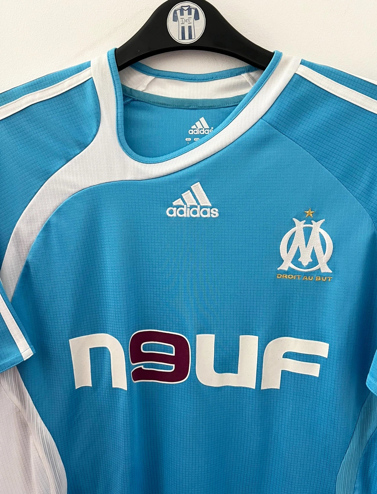 Maillot de foot vintage extérieur bleu et blanc de l'OM 2006/2007. On peut retrouver l'équipementier Adidas et le sponsor Neuf. Le maillot est floqué du numéro 7 Franck Ribery. Il s'agit d'un maillot authentique d'époque.