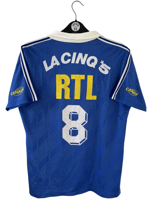 Maillot de foot vintage extérieur bleu du PSG saison 1988/1989. On peut retrouver l'équipementier Adidas et le sponsor RTL, La Cinq et Canal +. Il s'agit d'un maillot authentique d'époque.